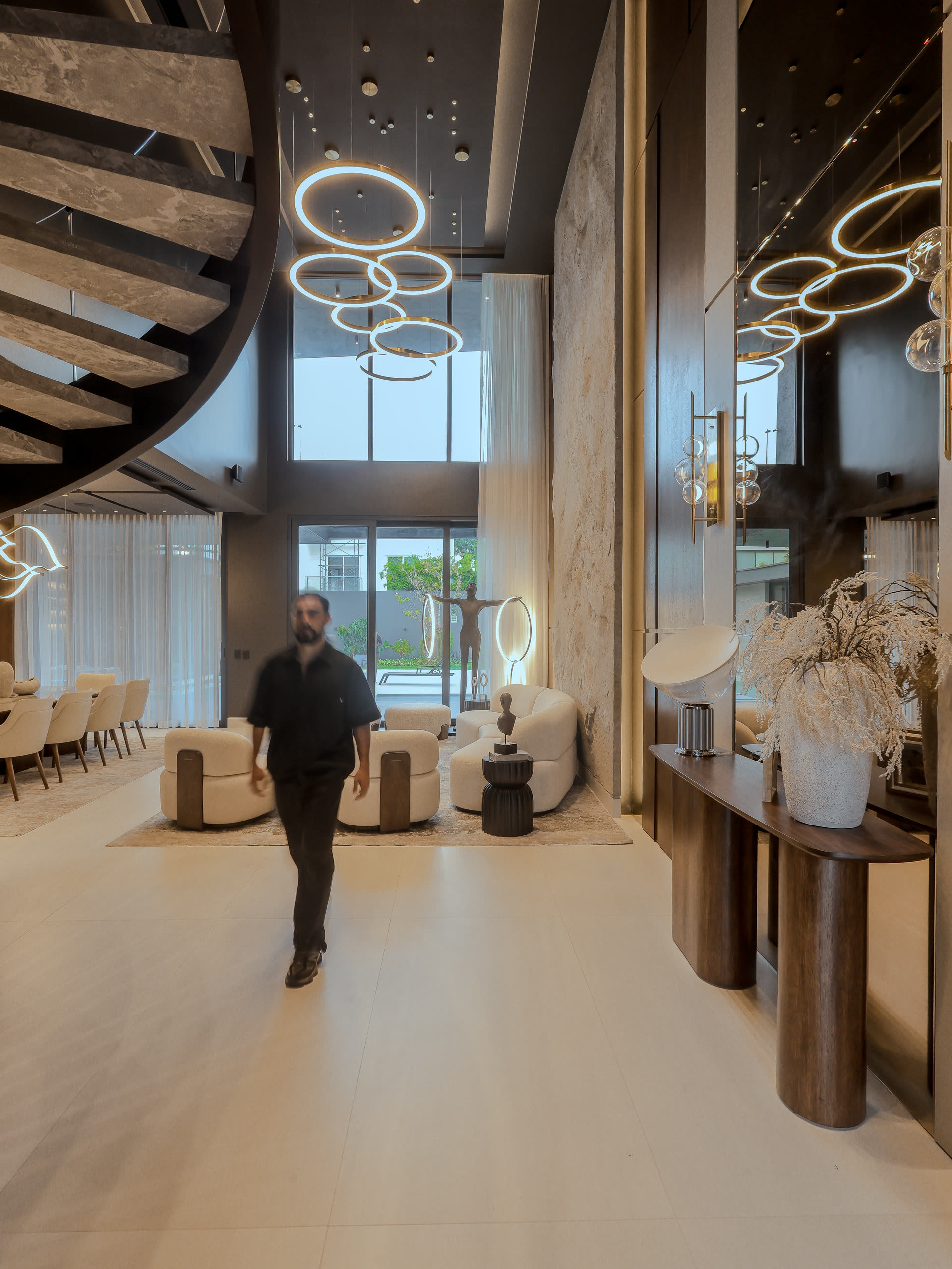 Hall de doble altura de Casa Cueva construida, con muro de piedra y lámparas circulares