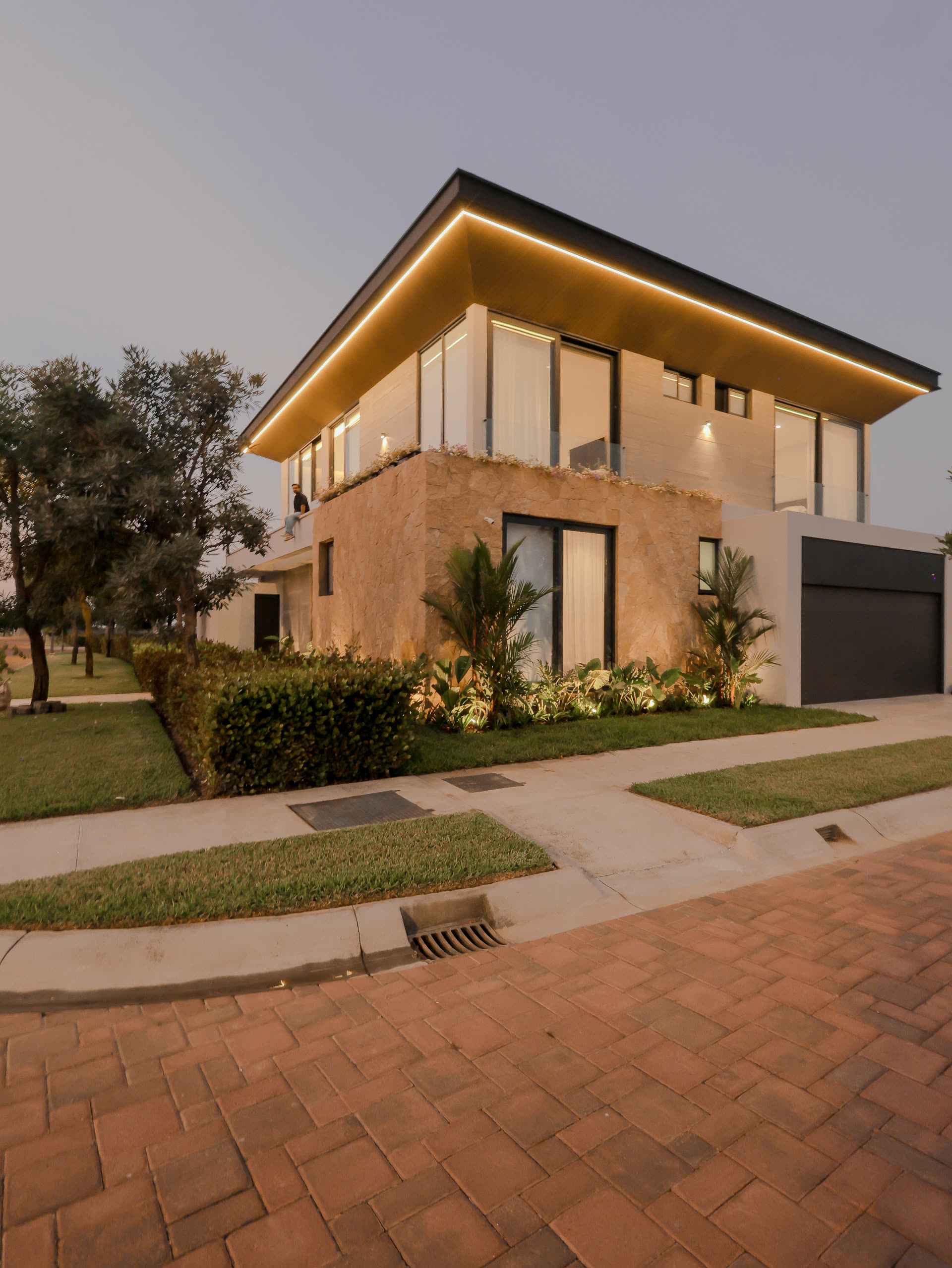 Casa MM en esquina al atardecer, con cubierta en voladizo y línea de luz