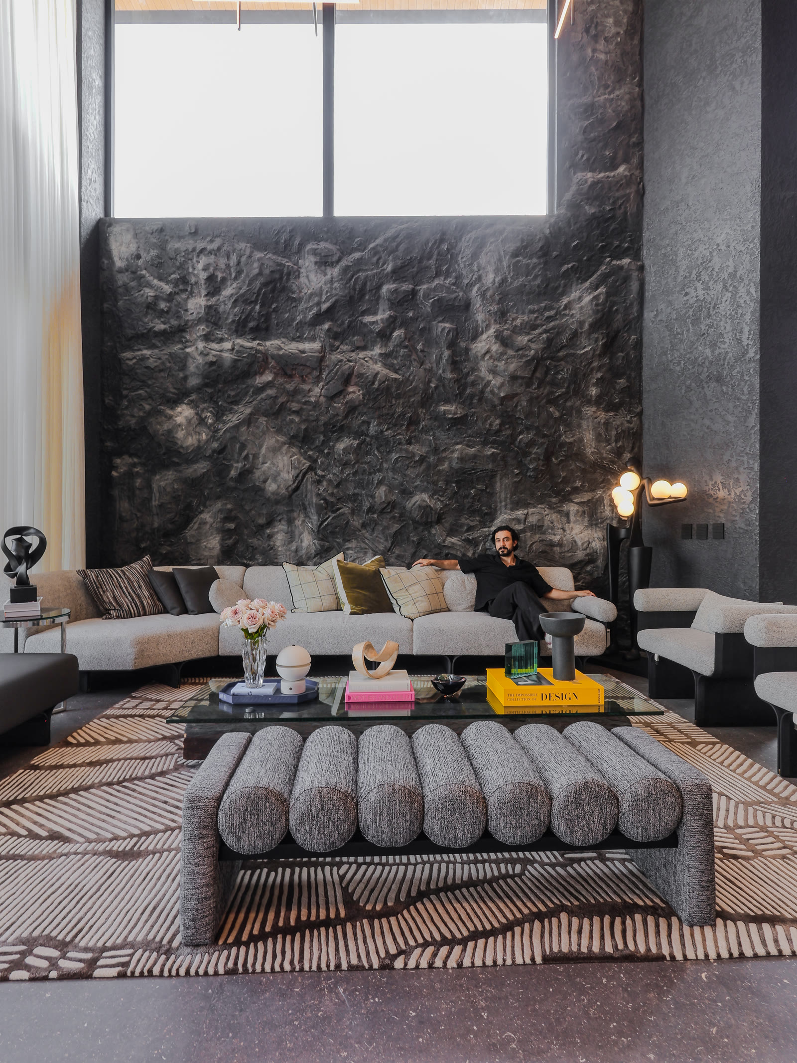 Sala de doble altura de Casa H1 con muro escultórico de roca
