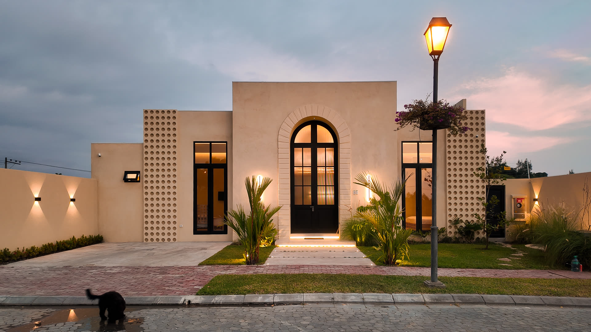 Ingreso de la casa al anochecer, con puerta de arco iluminada